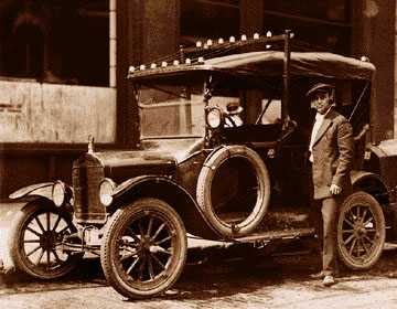 Patrolman and radio operator Walter Stick stands by one of the city's first radio-dispatched Police cars, a Ford Model T. Note the antennae on the roof.