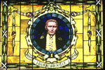 Framed and mounted stained glass window depicting the front head and shoulders profile of a man with the words 