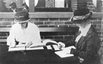 Image showing two women sitting at a table, copying text into Braille.